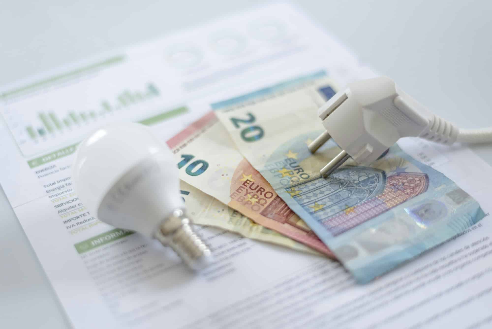 a white electric cap, a light bulb and euro banknotes on an electric bill.