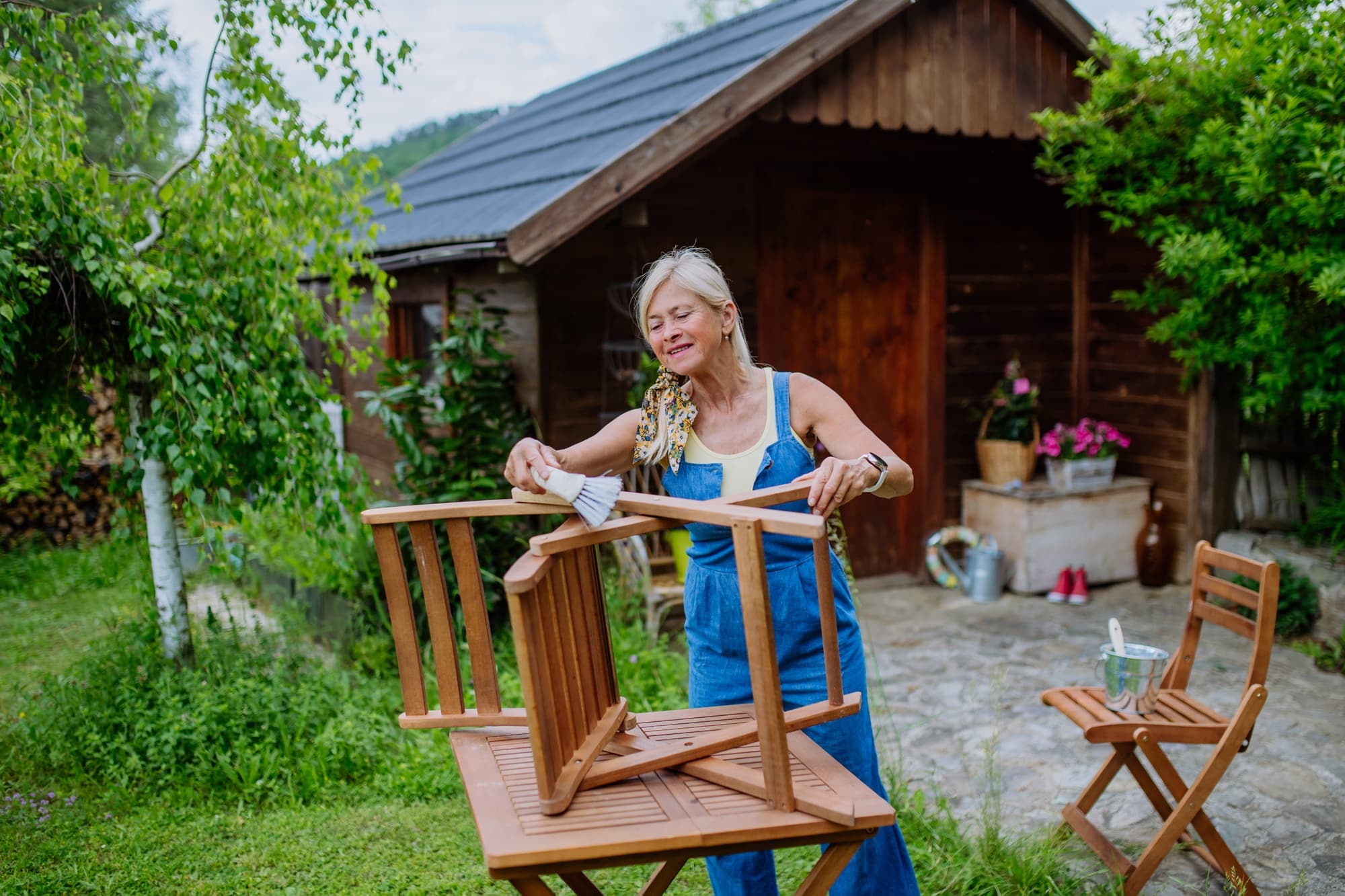 Senior woman cleaning garden furniture and getting the garden ready for summer